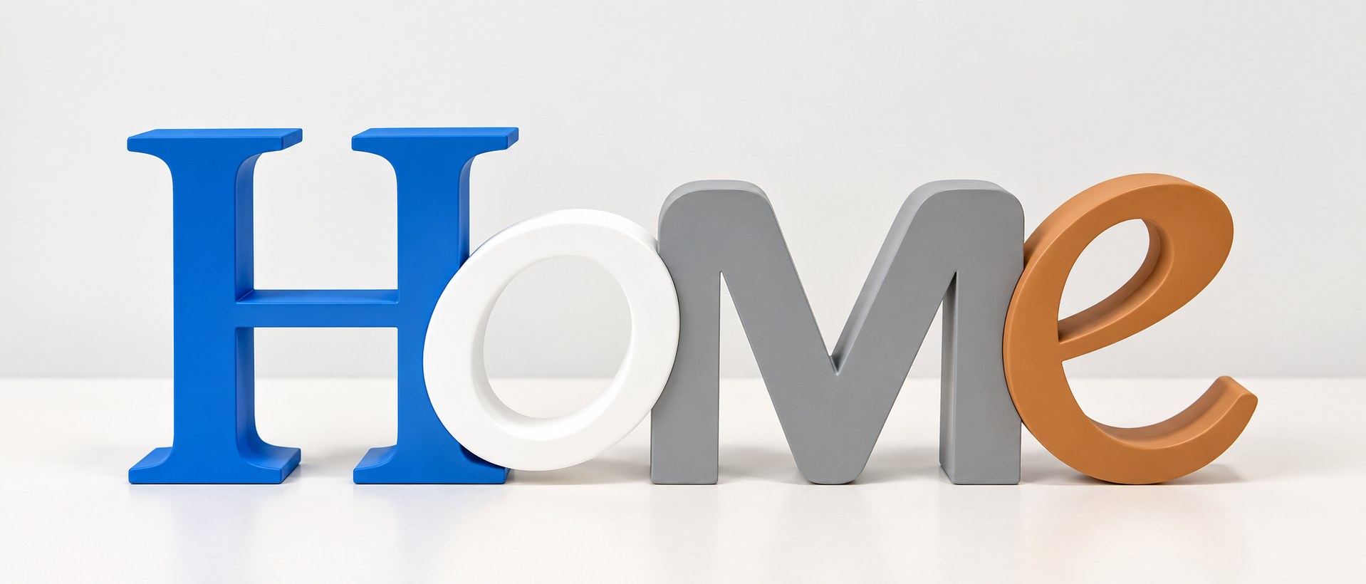 Letras decorativas HOME en azul, blanco, gris y marrón sobre una mesa blanca